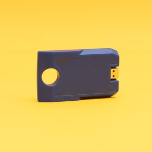 Angled front view of the blue digital talking book cartridge against a yellow background. The cartridge has a circular hole on one end and a USB port on the other, and it reads "4GB."