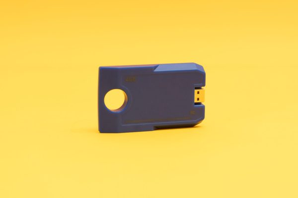 Angled front view of the blue digital talking book cartridge against a yellow background. The cartridge has a circular hole on one end and a USB port on the other, and it reads "4GB."