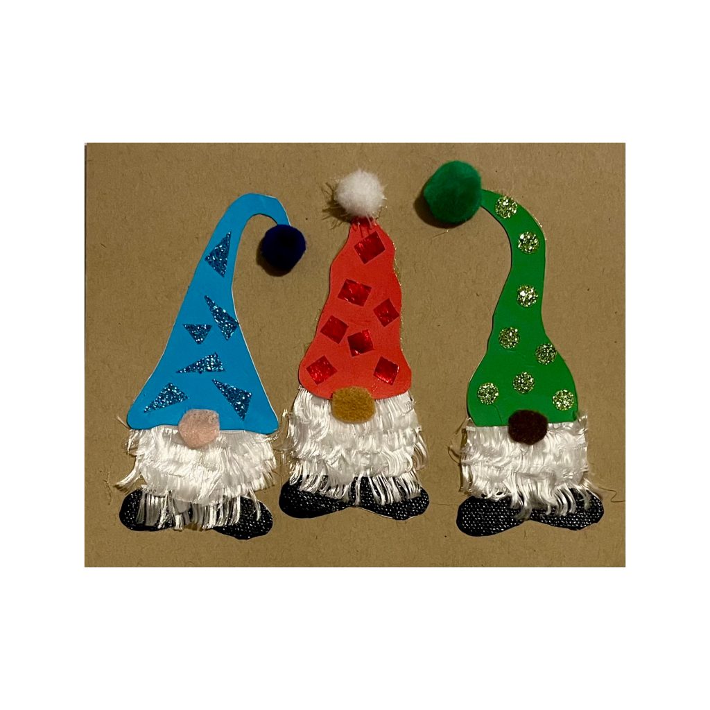 Three gnomes wearing tall decorated, textured stocking-caps, one blue, one red, and one green, standing side by side. Each gnome has a silky white beard, a felt nose, and textured boots.