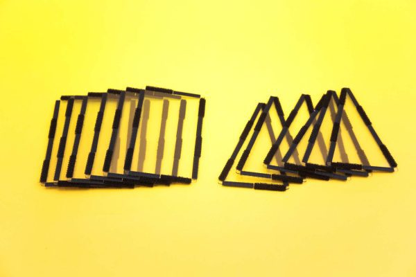 Two fanned-out stacks of clear plastic pieces with black Velcro borders. On the left are rectangle pieces, and on the right are isosceles triangles.