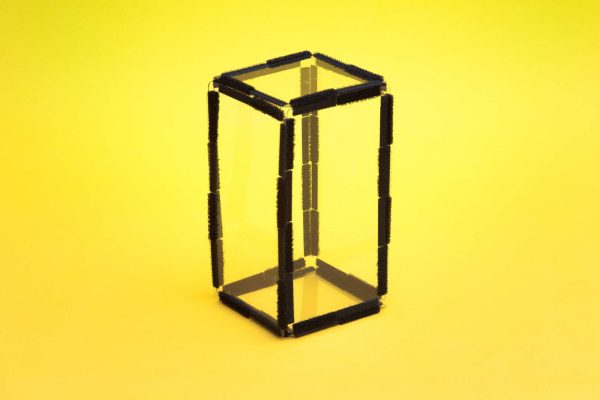 Four clear plastic rectangular pieces arranged with two squares on a yellow background to form a rectangular prism.