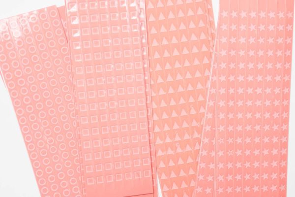 Close up of overlapping perforated shape strips including circles, squares, triangles, and stars.