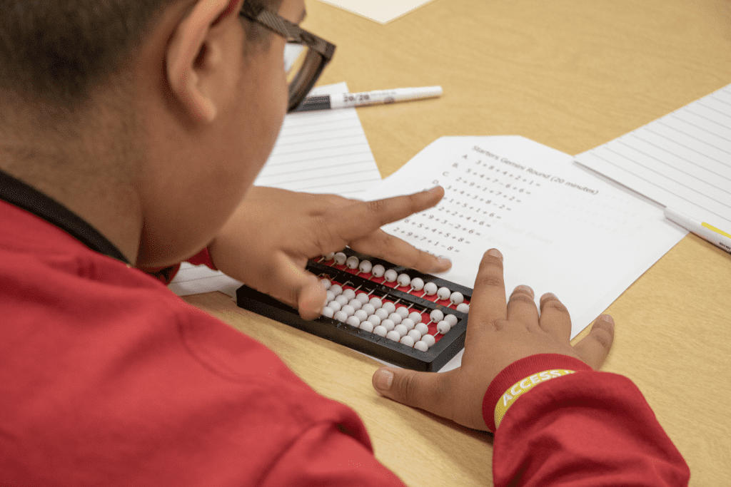 Young student with both hands on an abacus competing in the 2022 Abacus Bee.