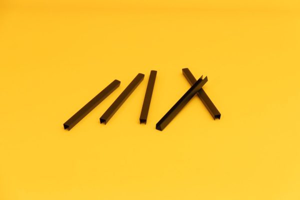: A close up of six black U-Channels laid out on a yellow background.