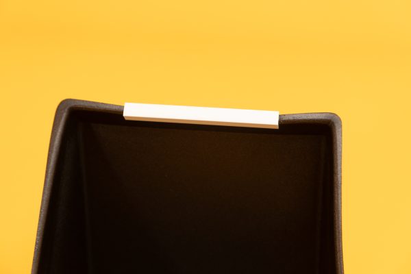 A close up image of the white U-channel attached to a black calendar box against a yellow background.