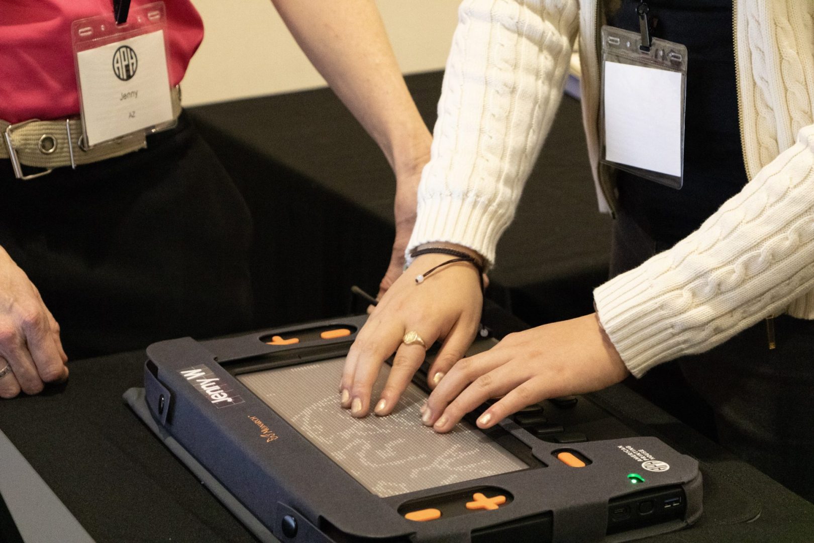 A student feels a tactile graphic on the Monarch's tactile display with two hands as an APH employee stands beside them.