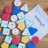 A variety of Reach & Match Number Tiles spread out on a wooden floor on top of a branded "Reach & Match" canvas bag.