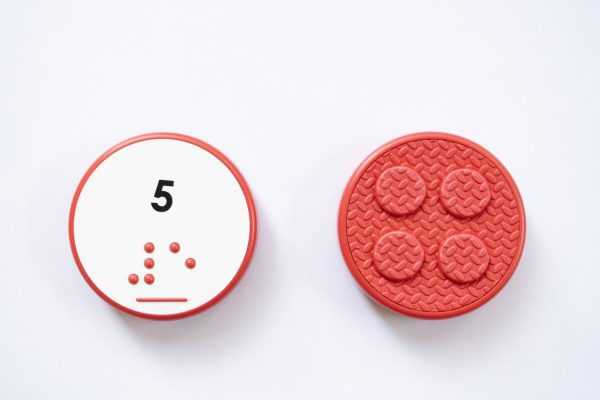 Close up comparison of the front and back of a red circular UEB Reach and Match number tile showing the number 5 in braille and print. The back of the piece is textured.