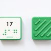Close up comparison of the front and back of a green square UEB Reach and Match number tile showing the number 17 in braille and print. The back of the piece is textured.
