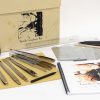 Close up of the tongs and Tactile Graphics Kit print guidebook laid out against a white background. Other kit components lay next to these out of focus.