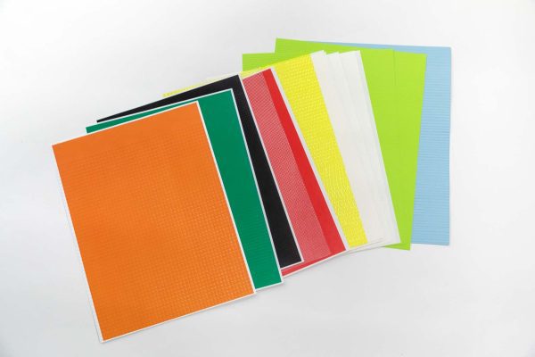 A stack of multi-colored textured paper spread across on a white surface.