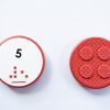 Front and back of red circular Reach & Match Number tile showing the number 5 in Nemeth braille and print. The back side is textured.