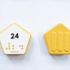 Front and back of yellow hexagonal Reach & Match Number tile showing the number 24 in Nemeth braille and print. The back side is textured.