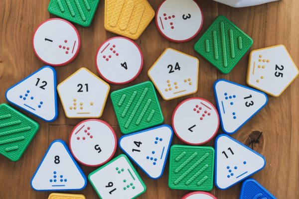 A variety of Nemeth Reach and Match number tiles spread out on a wooden surface.