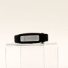 OpticAware device on a clear pedestal against a white background. A silver oval-shaped module fits into a black smart-watch style wearable.