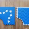 Two blue Reach & Match mats side by side demonstrating the differences between the textured side and the side with triangular cut-outs for tiles and a traceable path.