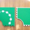 Two green Reach & Match mats side by side demonstrating the differences between the textured side and the side with square cut-outs for tiles and a traceable path.