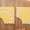 Two yellow Reach & Match mats side by side demonstrating the differences between the textured side and the side with hexagonal cut-outs for tiles and a traceable path.