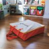 The orange and white Reach and Match Light carrying case on a wooden floor.