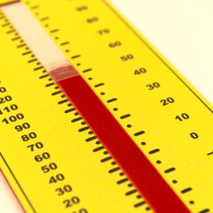A close up of the yellow Tactile Demonstration Thermometer on a white background. In the center of the thermometer is a red velvet "mercury column" that can be adjusted with a clear easy-grip indicator. The edges of the photo are blurred with a crisp focus in the center of the thermometer.