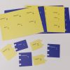 Overhead shot of Tactile Ionic Bonding Kit pieces on a white background. Above are four perforated blue and yellow sheets that contain the puzzle pieces, and below are six examples of the puzzle pieces punched out.