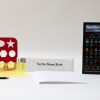 All the components of the Tactile Shape Slate kit, including a yellow slate, a large red stencil, and the guidebook, all laid out on a white background.