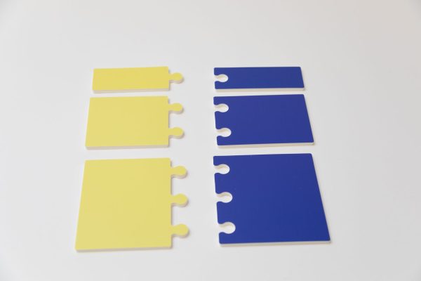 A variety of yellow and blue subunits laying face down in two rows. Both colors include subunits that have between one and three notches/connection points.