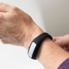Two hands of a woman adjusting the closure on an OpticAware band on her wrist.