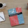An overhead shot of a copy of Accessible Science sitting on a wooden surface next to a mug of black coffee, a notebook and pen, and a green and red succulent.
