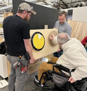 A man in a wheelchair reaches out to touch a tactile model.