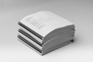 A stack of all the volumes included in the BOP 2nd Grade Unit 2 Braille Teacher's Kit.