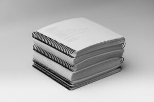 A stack of all the volumes included in the BOP 2nd Grade Unit 7 Braille Teacher's Kit.