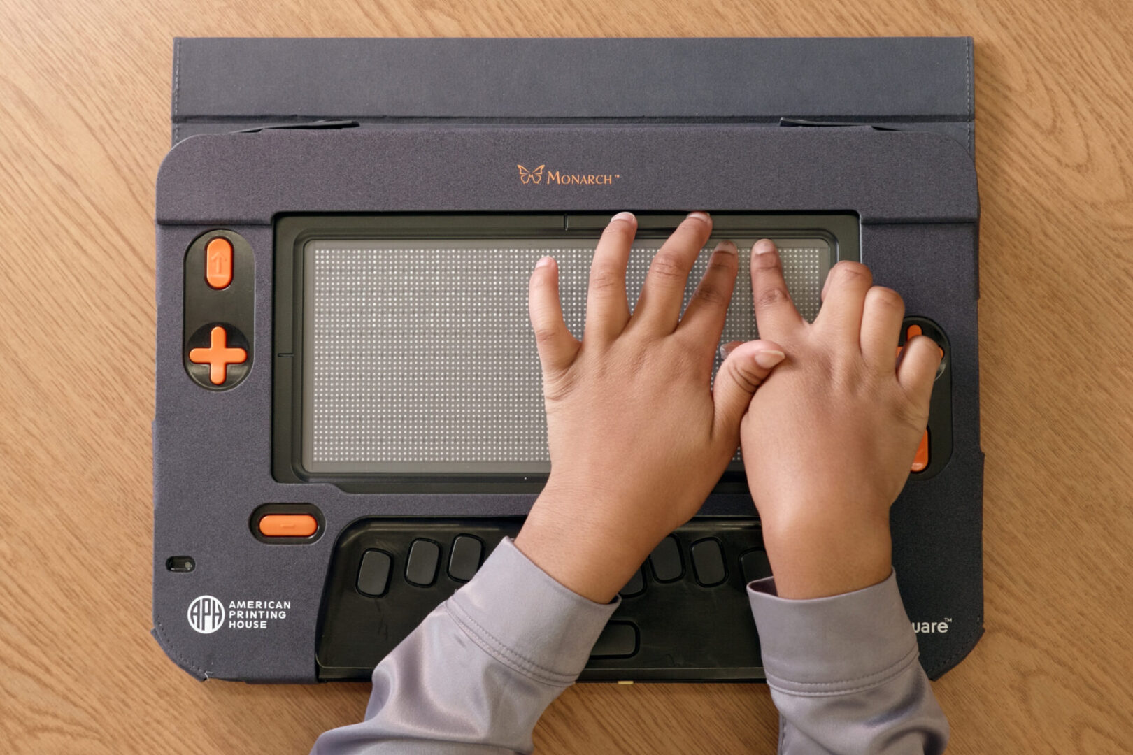 Two hands reading braille on Monarch.