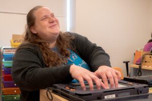A student smiles as her hands explore the braille on Monarch's screen.