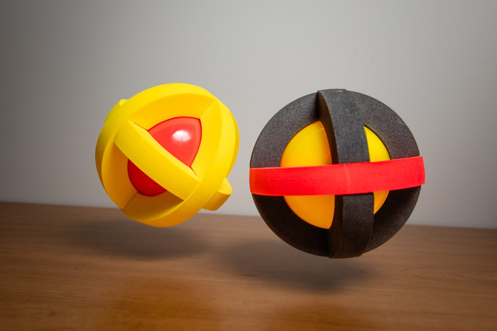 Two Astro Adventure Balls midair over a wooden desk.